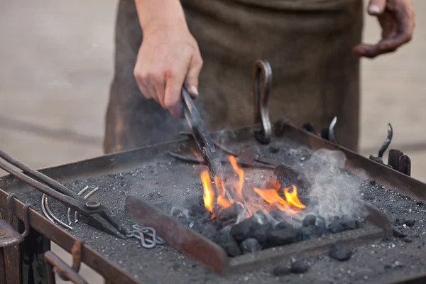 Brasas, fuego, humo, herramientas y las manos de un herrero — Foto de Stock
