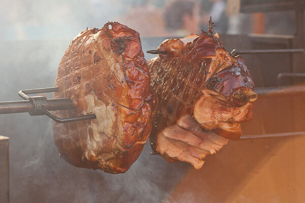 Huge chunks of pork roasting on a spit