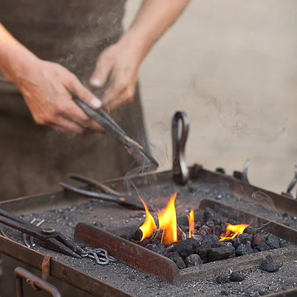 Угли, огонь, дым, инструменты и руки кузнеца — стоковое фото