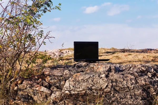 笔记本电脑站在一块岩石对蓝蓝的天空 — 图库照片