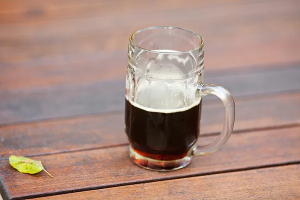 Caneca com cerveja escura em pé sobre a mesa — Fotografia de Stock