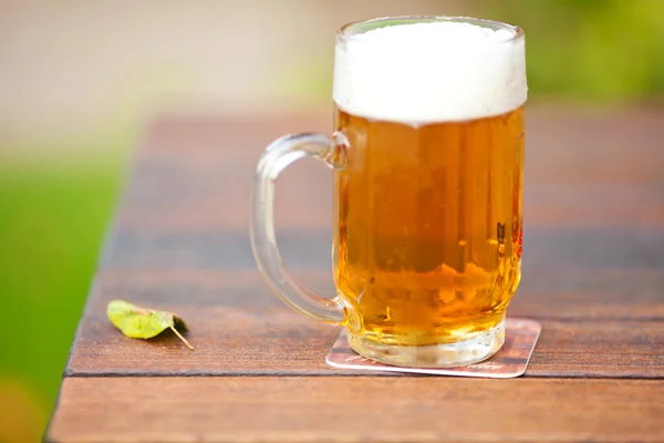 Taza con cerveza ligera de pie sobre la mesa — Foto de Stock