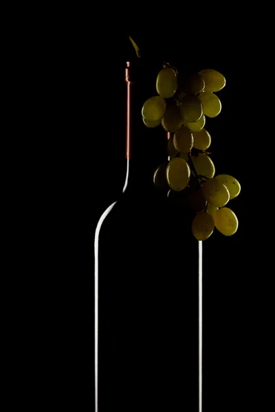Bottiglia di vino e grappolo d'uva su fondo nero — Foto Stock