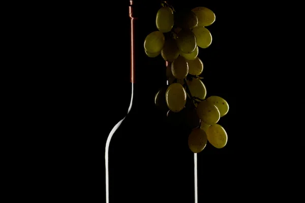 Flaska vin och en massa druvor på svart bakgrund — Stockfoto