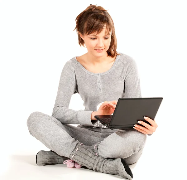 Ung kvinna i pyjamas med laptop — Stockfoto