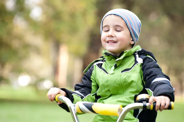 Kleine jongen rijden fiets buiten op de weide met ogen gesloten — Stockfoto
