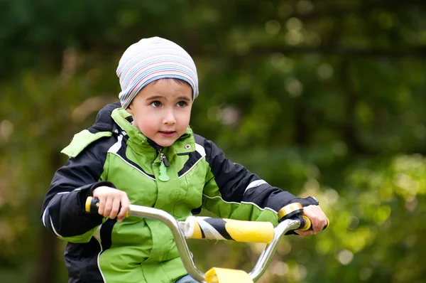 Little boy riding bike outdoors in forest — Stock Photo, Image
