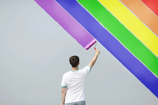 Hombre joven pintando arco iris — Foto de Stock