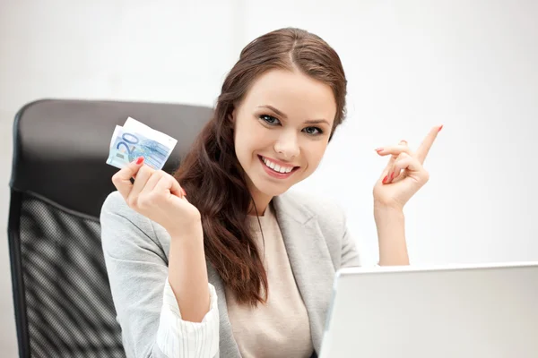 Счастливая женщина с компьютером и евро наличными деньгами — стоковое фото