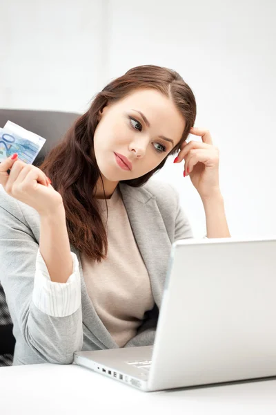 Mujer pensativa con computadora y dinero en efectivo en euros — Foto de Stock