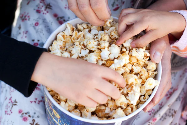 stock image Children eat popcorn out of a paper bucket, close-up