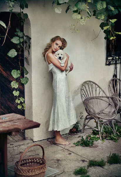 Leuke vrouw in witte jurk knuffelen haar puppy — Stockfoto