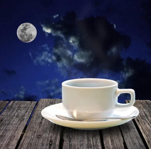 Hot coffee on wooden table at night — Stock Photo, Image