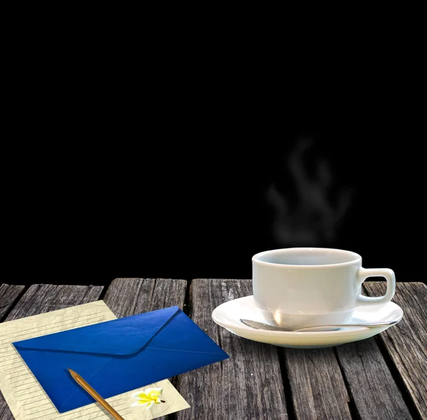 Forró kávét és a fából készült asztal fekete háttér előtt levelet — Stock Fotó