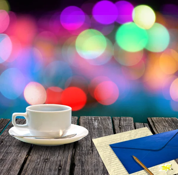 Hot coffee and letter on wooden table with colorful bokeh background — Stock Photo, Image