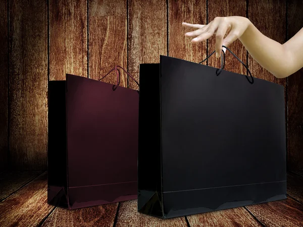 木製の背景を持つ女性手に釉薬ショッピング バッグ — ストック写真