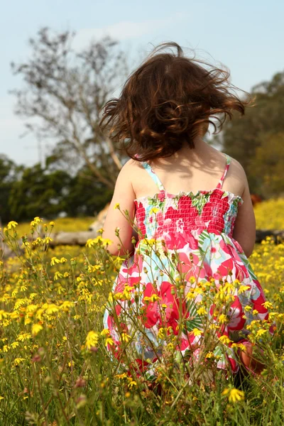Νεαρό κορίτσι στέκεται σε ένα πεδίο της κίτρινα λουλούδια — Φωτογραφία Αρχείου
