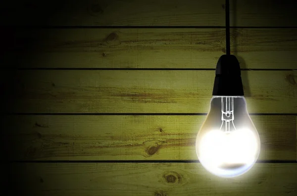 Bulb over wooden wall — Stock Photo, Image