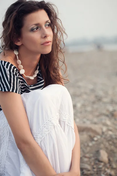 Zamyšlený bruneta žena sedí na pobřeží — Stock fotografie