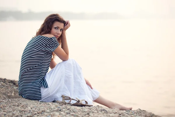 美丽的女人坐在海滩上 — 图库照片