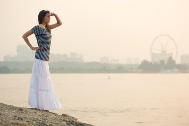 Brunette woman standing on beach clipart