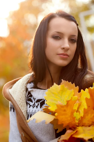 Brunette holding oak leaves — Stock Photo, Image