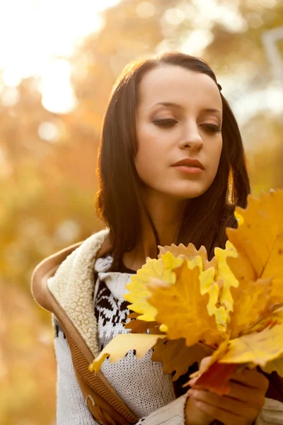 Brunette holding yellow leaves — Stock Photo, Image