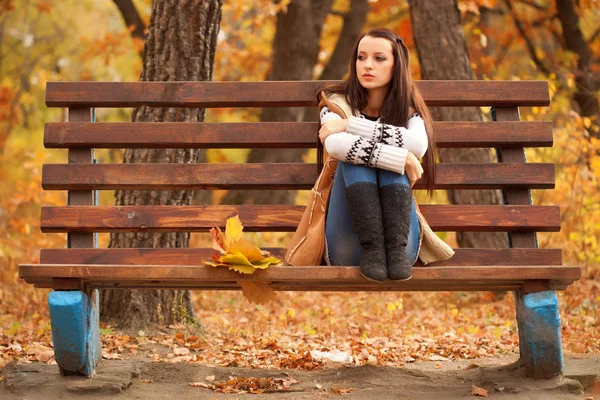 Женщина сидит на коричневой скамейке — стоковое фото
