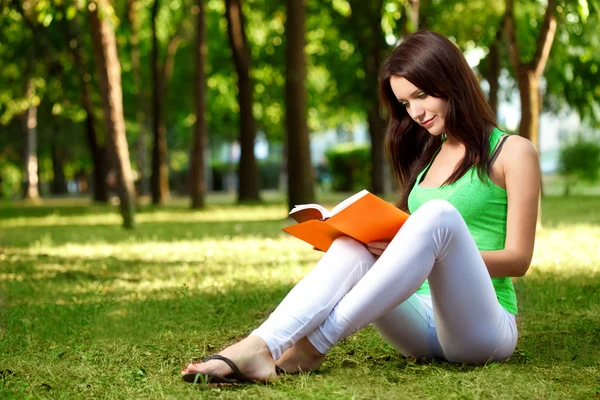 Kvinna sitter på marken och läsa bok — Stockfoto