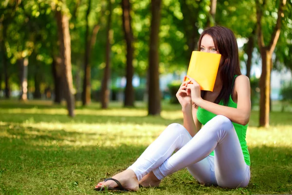 Kobieta obejmują twarz z książki w parku — Zdjęcie stockowe