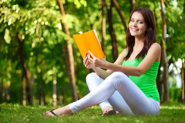 Женщина читает книгу в зеленом парке — стоковое фото