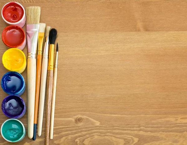 Tintas e escovas em mesa de madeira — Fotografia de Stock