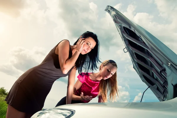 Två unga kvinnor med trasiga bil på en väg — Stockfoto