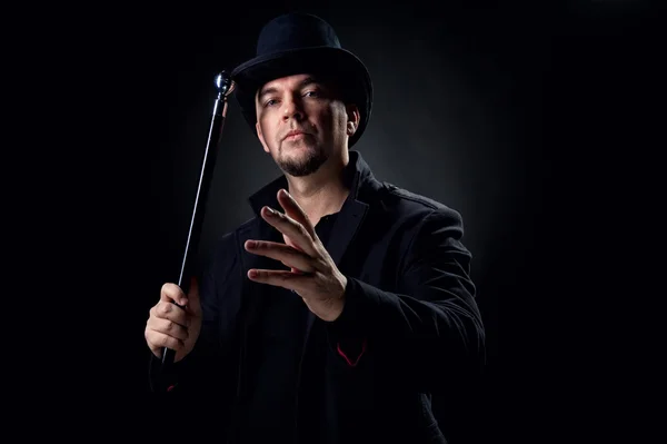 Przystojny mężczyzna, ubrany w czarny kapelusz i płaszcz, trzymając kij — Zdjęcie stockowe