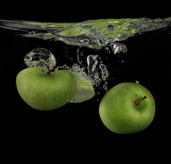 Maçãs verdes frescas salpicando na água — Fotografia de Stock