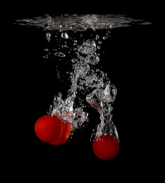 Pomodori ciliegia spruzzi in acqua — Foto Stock