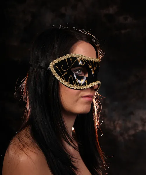 Moda chica morena con máscara posando sobre fondo oscuro — Foto de Stock