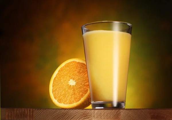 Un vaso de jugo de naranja en una tabla de madera . — Foto de Stock