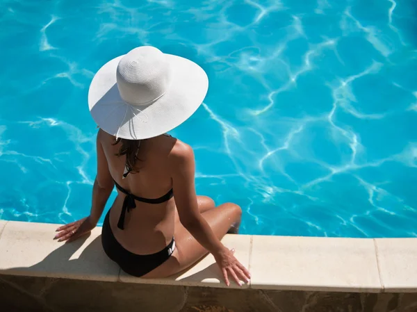 Mladá žena sedící na římse bazénu. — Stock fotografie