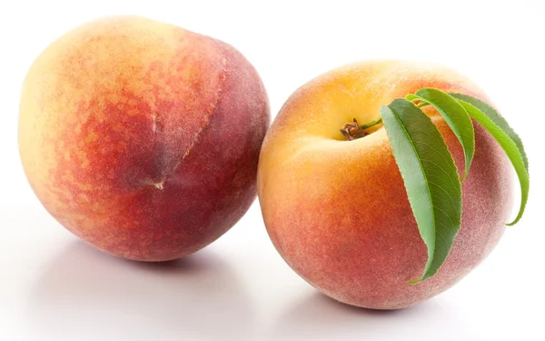 Zwei reife Pfirsiche mit Blättern — Stockfoto