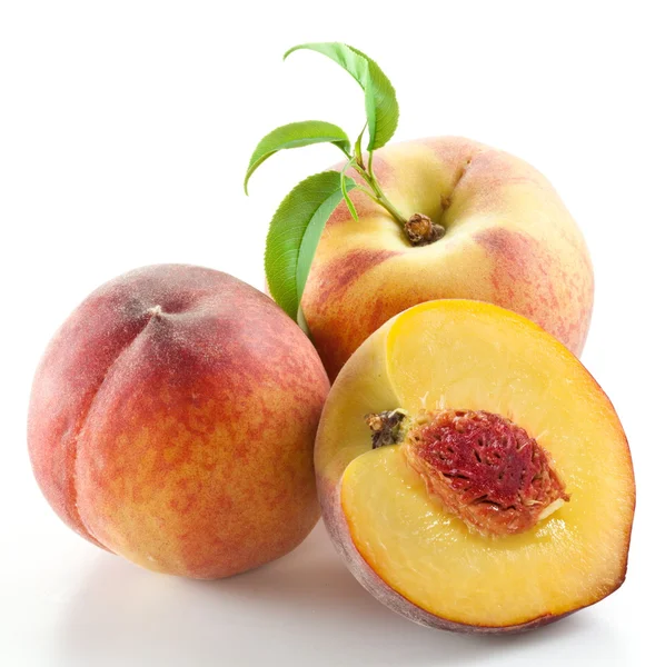 Стиглі персикові плоди з листям і скибочками — стокове фото