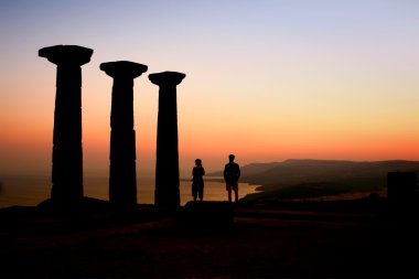 Two Tourists Watching The Sunset At The Athena Temple clipart