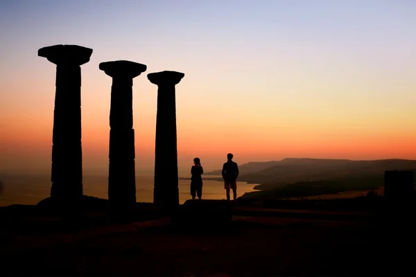 Két turisták nézni a naplementét az athena templom — Stock Fotó