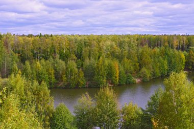 Cloudy sky and forest in autumn in river valley clipart