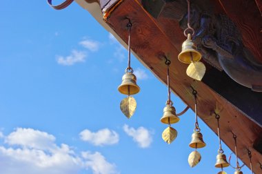 Bronze bells ringing in the wind under the roof of a Buddhist temple clipart