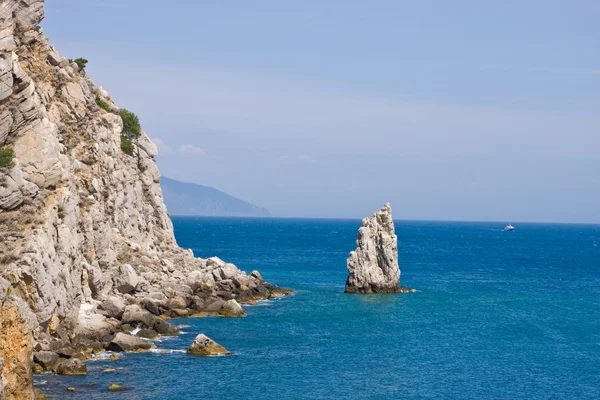 Море со скалами и лодкой — стоковое фото