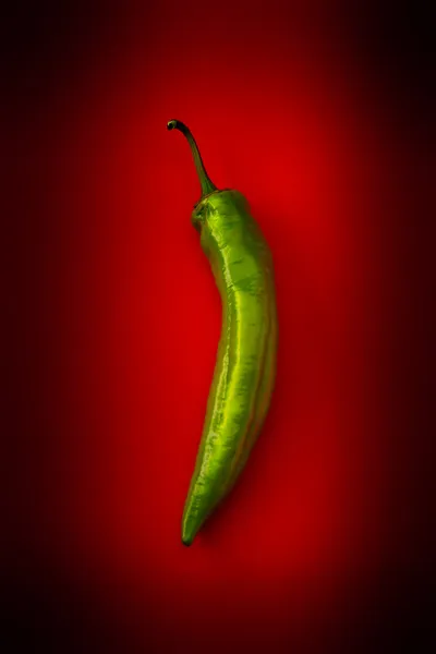 stock image Hot green pepper on a red background