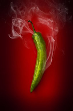 Hot green pepper on a red background clipart