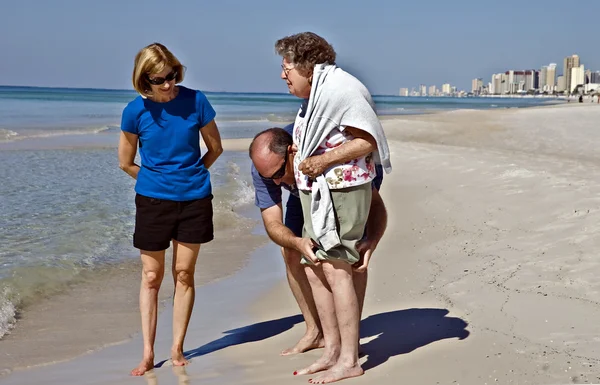 Hilfe für eine ältere Frau am Strand — Stockfoto