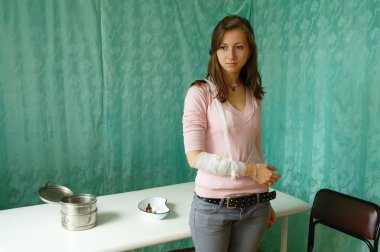 Klinikte bandajlı bir hasta bandajlı el ile üzgün bir kız
